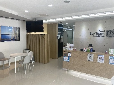 밝은 대기 공간과 접수대, 벽면에 서울버팀치과 영문 로고가 걸린 모습
